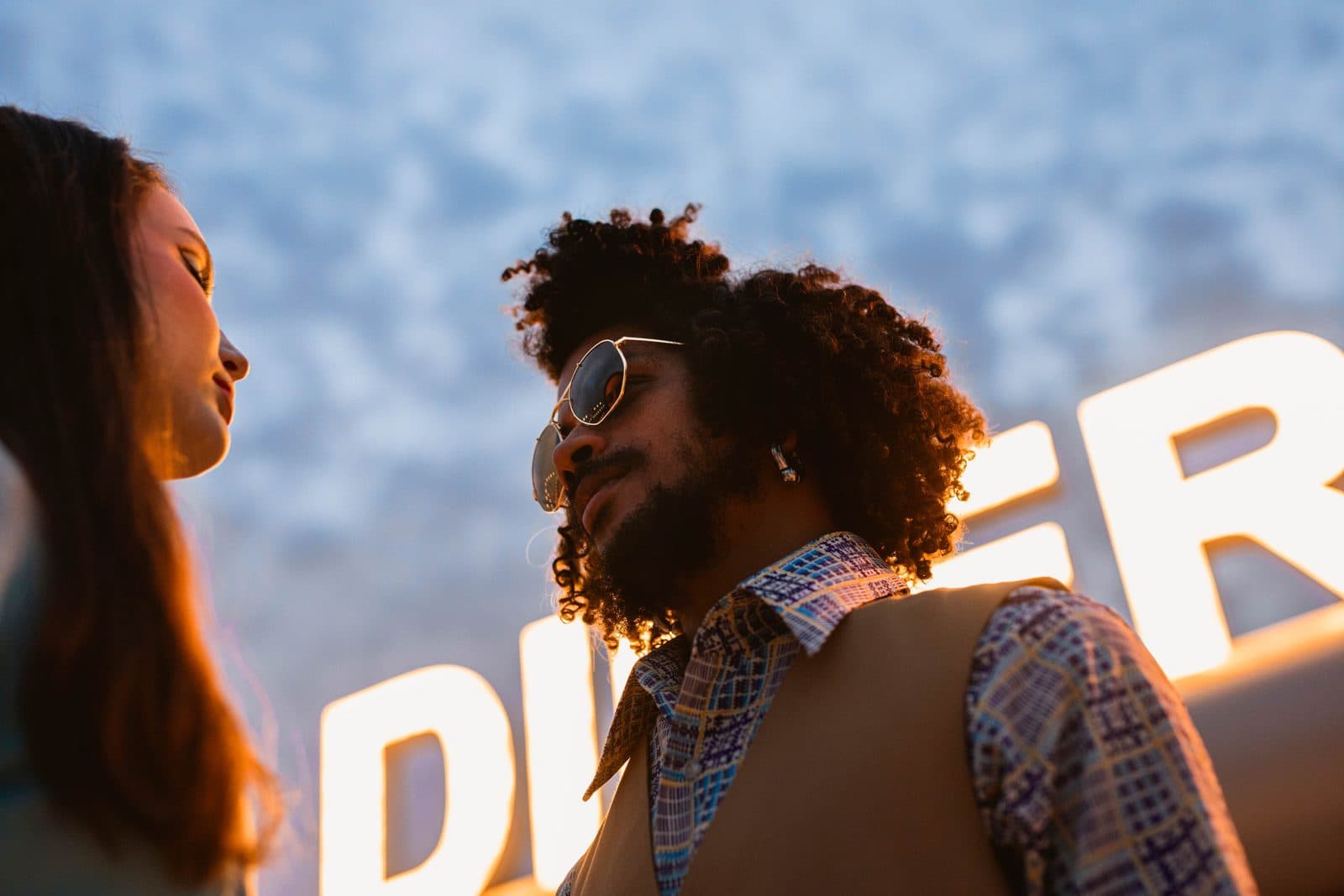 A man in sunglasses in front of a glowing sign at a live brand event